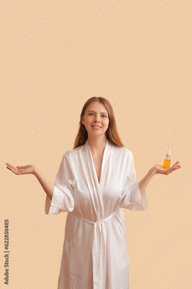 Pretty young woman with cosmetic oil on beige background