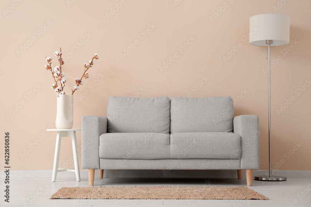 Interior of living room with sofa, lamp and cotton branches