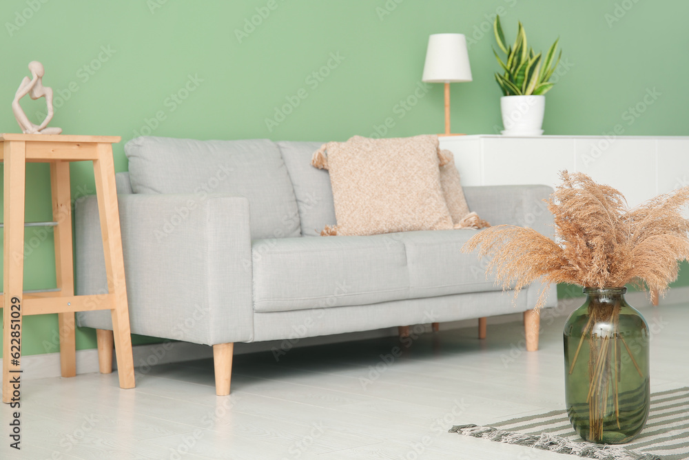 Interior of living room with sofa and vase with reed