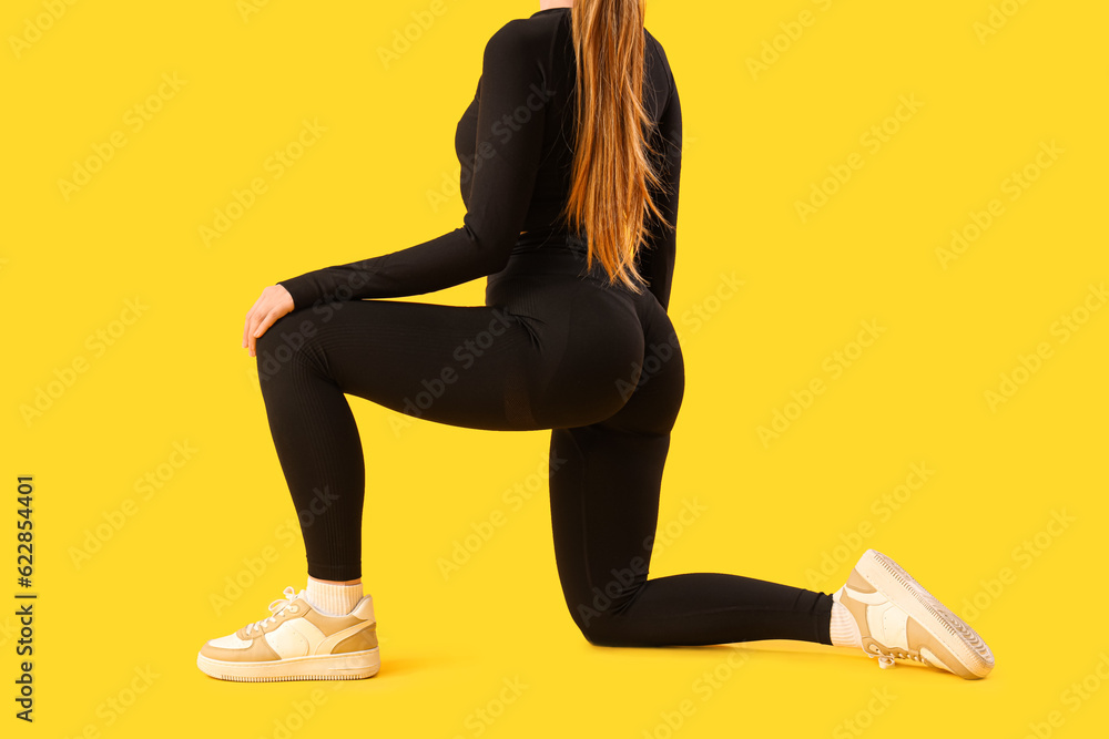 Young woman in sportswear on yellow background