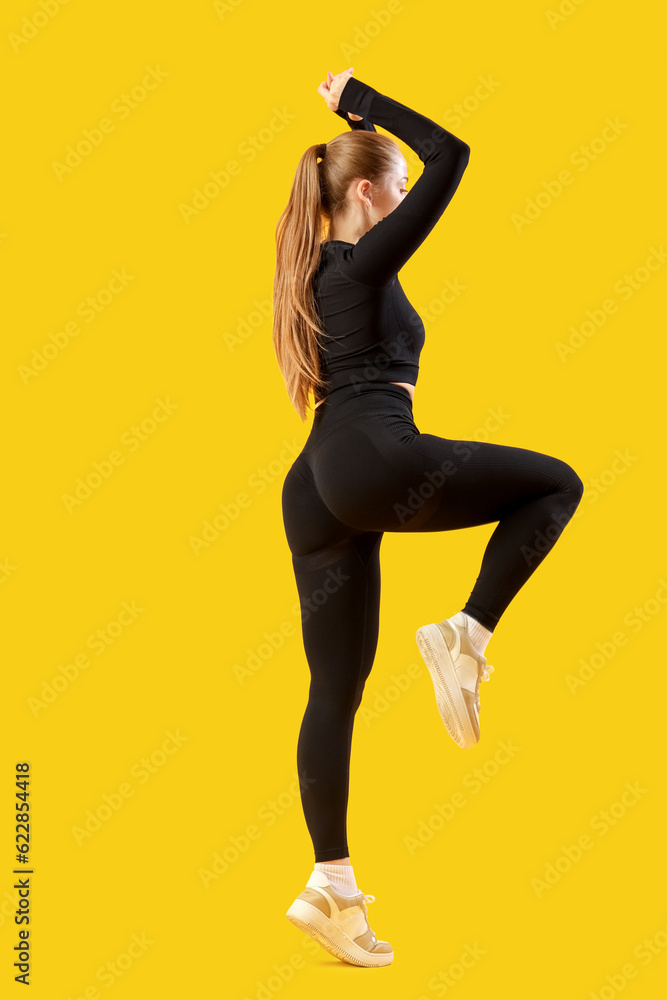 Young woman in sportswear on yellow background