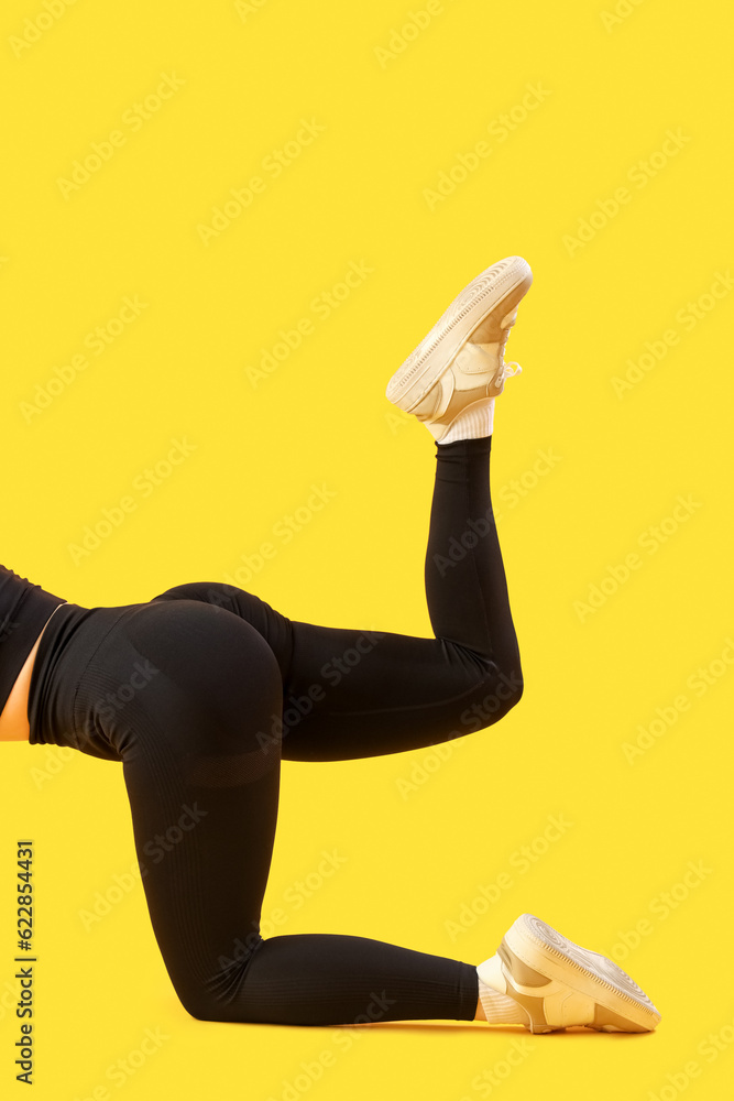 Sporty young woman in leggings on  yellow background