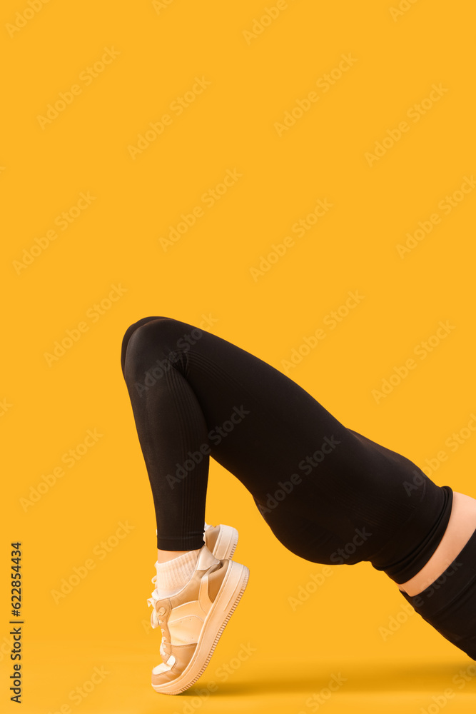 Sporty young woman in leggings on  yellow background