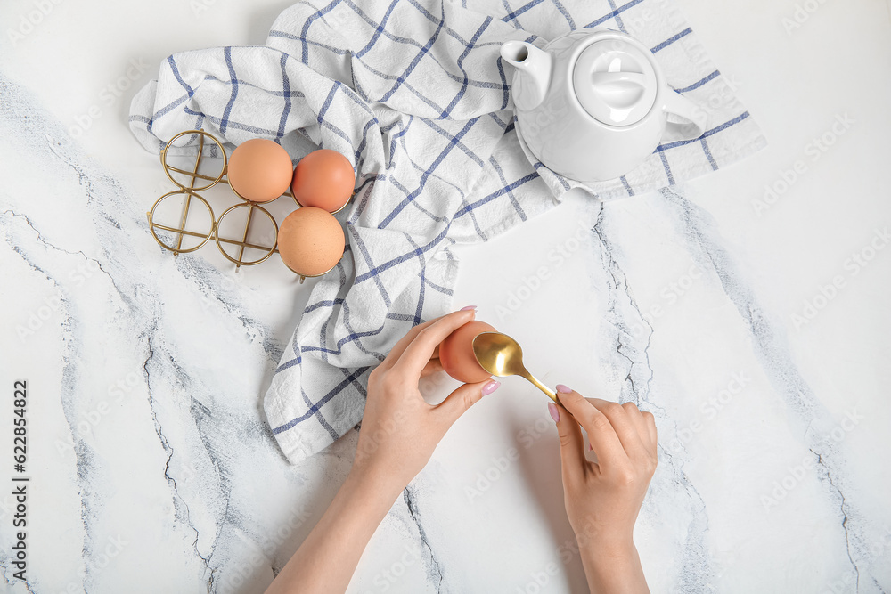 Woman peeling boiled chicken egg on white background