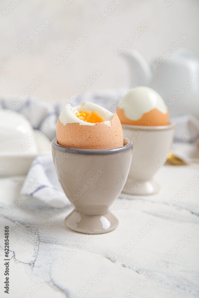 Holders with boiled chicken eggs on white background