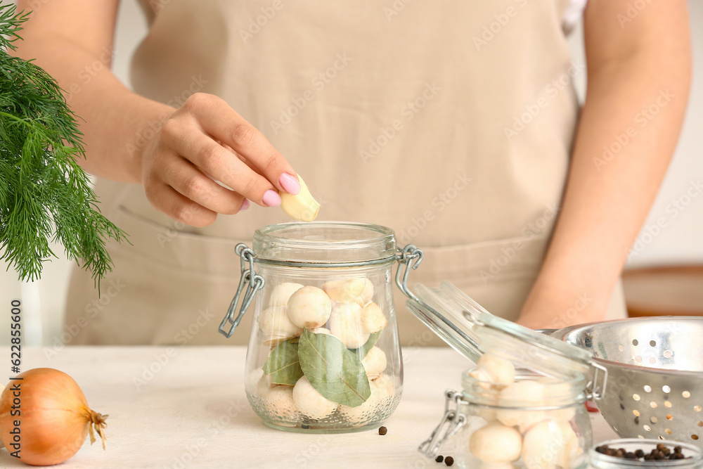 Woman preparing mushrooms for canning at table in kitchen