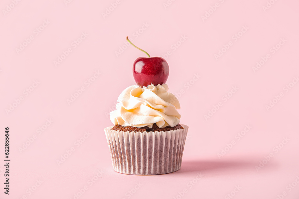 Tasty cherry cupcake on pink background