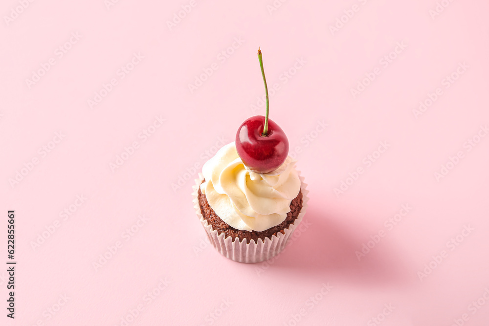 Tasty cherry cupcake on pink background