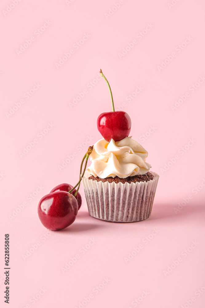 Tasty cherry cupcake on pink background