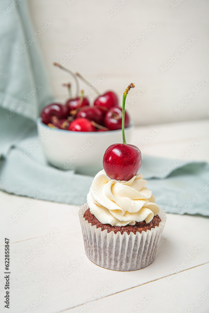 Tasty cherry cupcakes on table