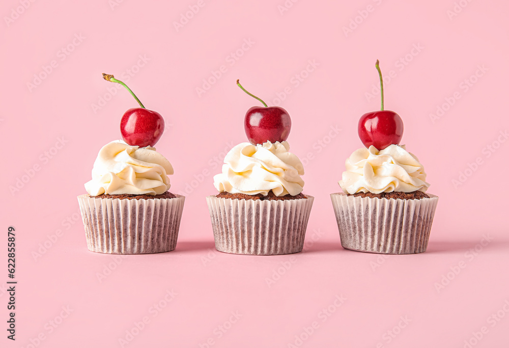 Tasty cherry cupcakes on pink background