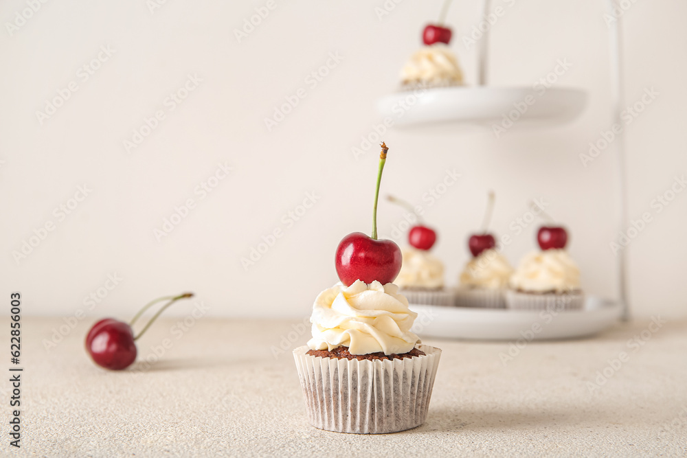 Tasty cherry cupcake on light background