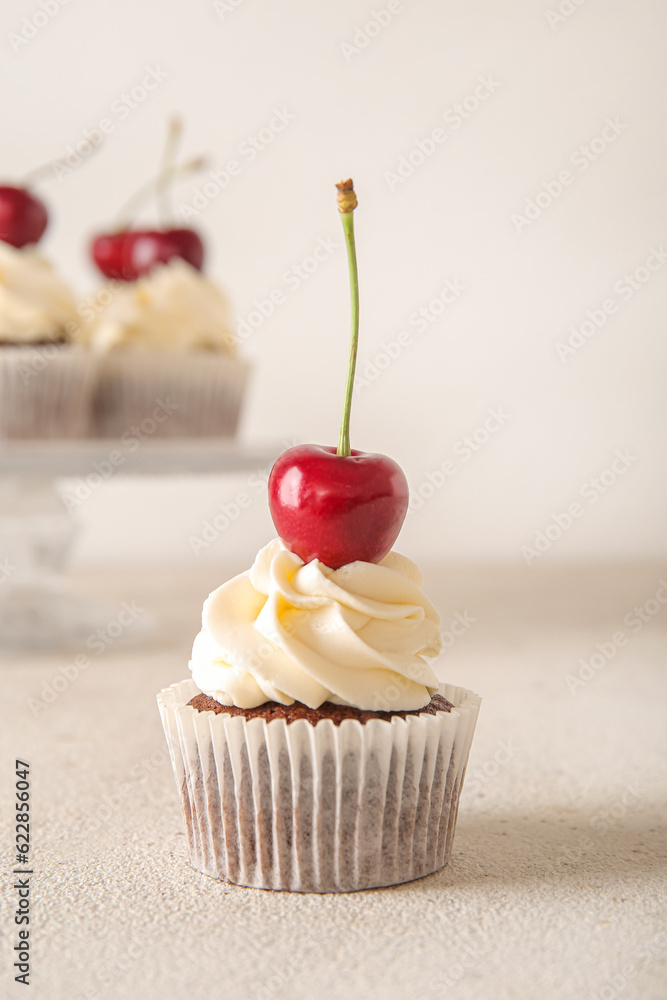 Tasty cherry cupcake on light background