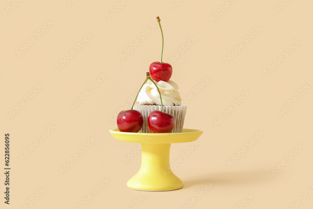 Stand with tasty cherry cupcake on beige background