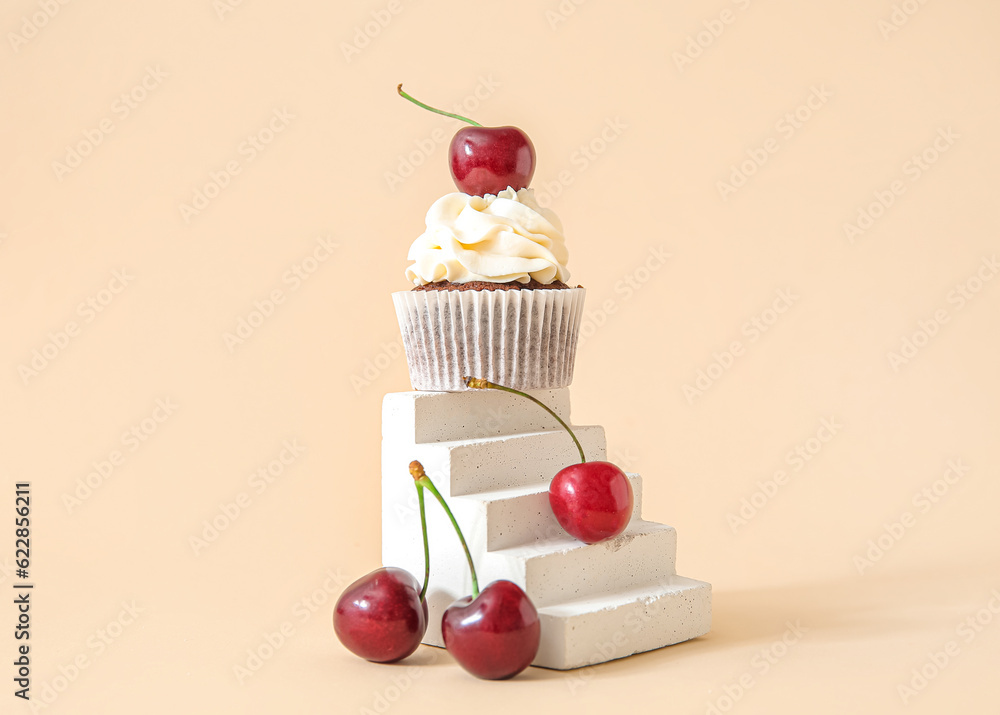 Decorative stand with tasty cherry cupcake on beige background