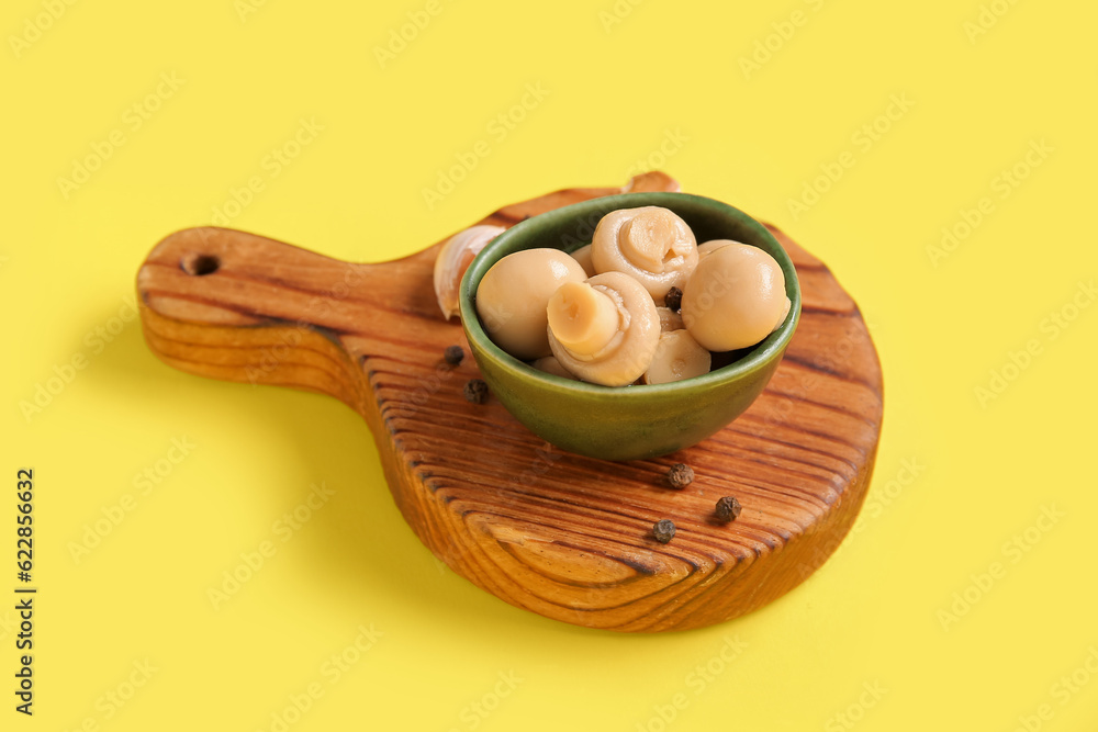 Bowl with canned mushrooms on yellow background