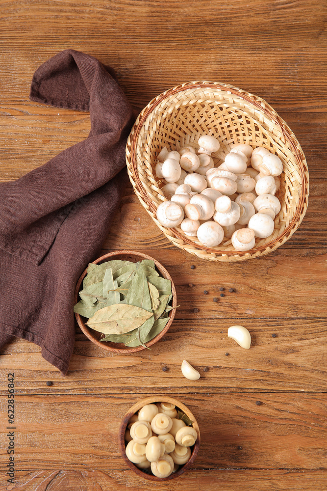 Tasty canned and fresh mushrooms with bay leaf on wooden background