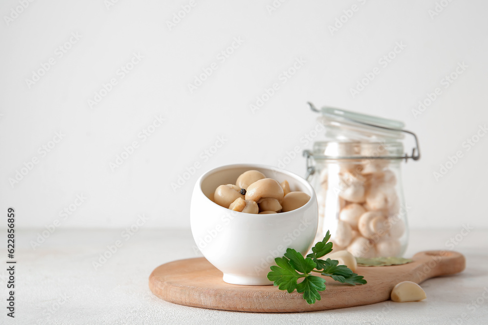 Bowl with canned mushrooms on light background