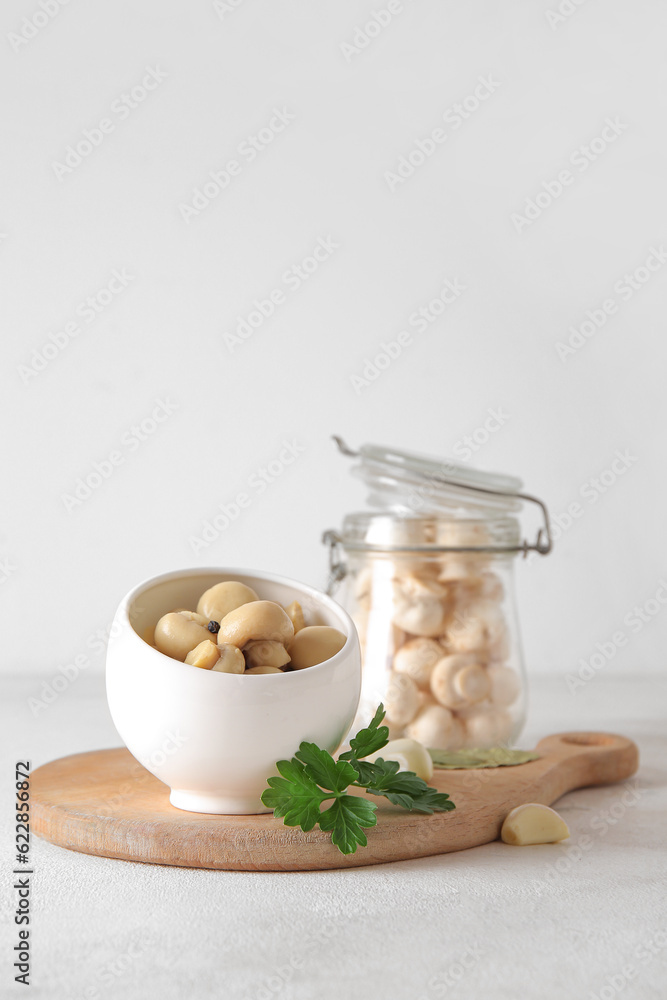 Bowl with canned mushrooms on light background