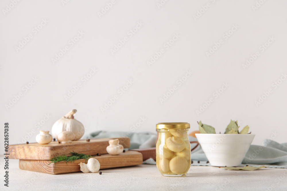 Jar with canned mushrooms on light background