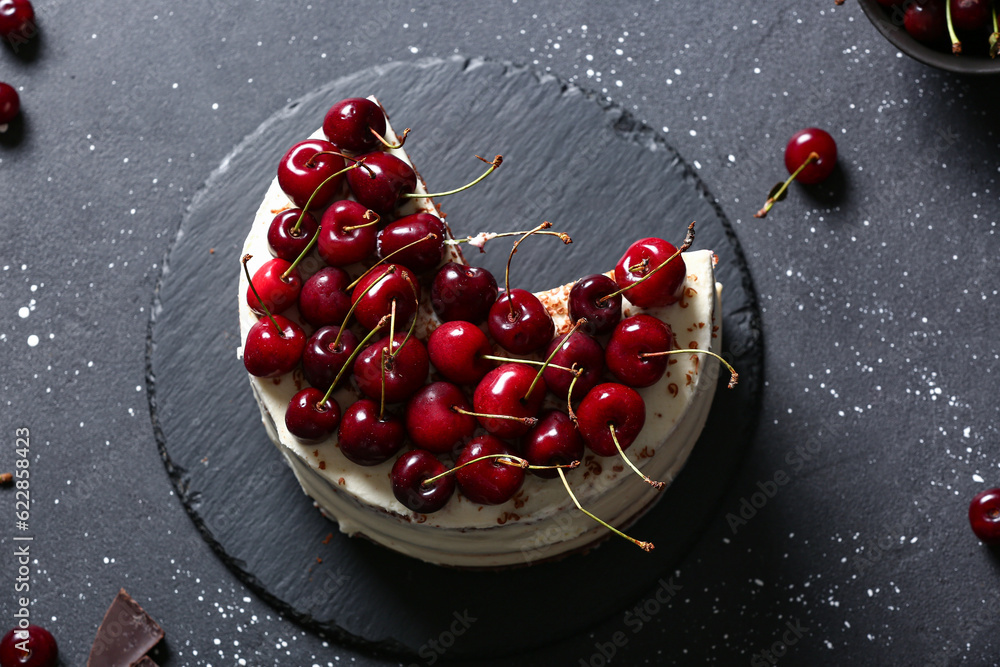 Board with tasty cherry cake on black table