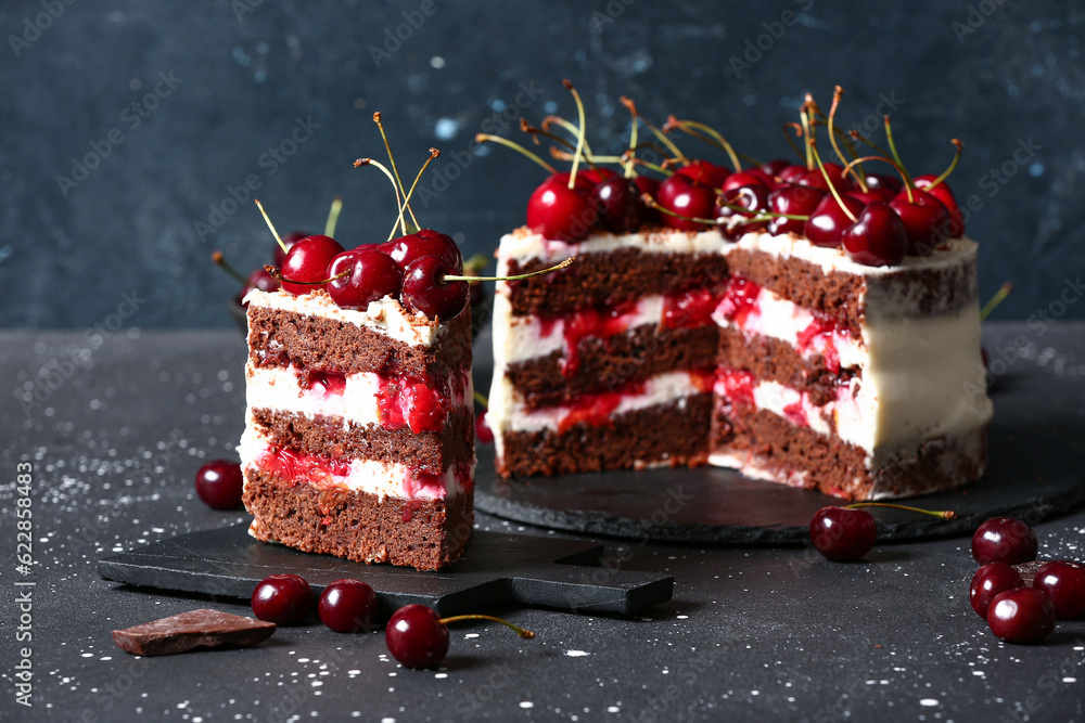 Tasty cherry cake and board with piece on black table