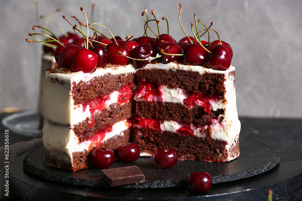 Board with tasty cherry cake on black table