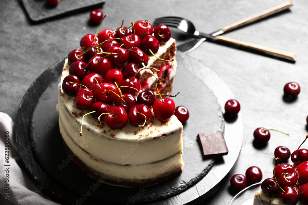 Board with tasty cherry cake on black table