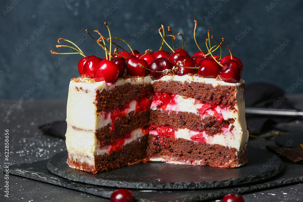 Board with tasty cherry cake on black table