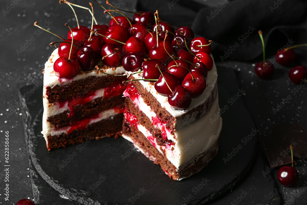 Board with tasty cherry cake on black table