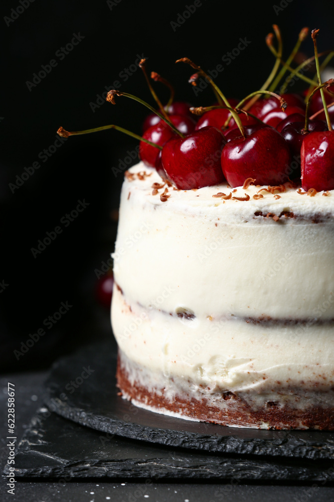 Board with tasty cherry cake on black table, closeup