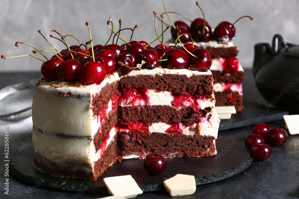 Board with tasty cherry cake on black table