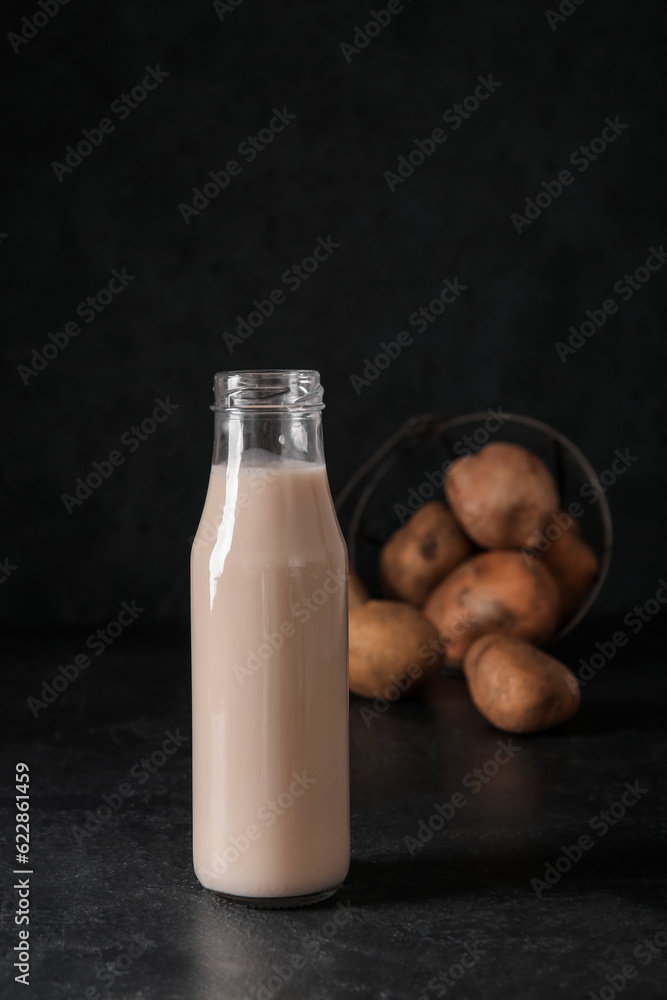 Bottle of tasty potato milk on black background