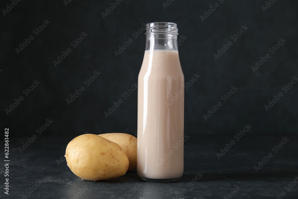 Bottle of tasty potato milk on black background