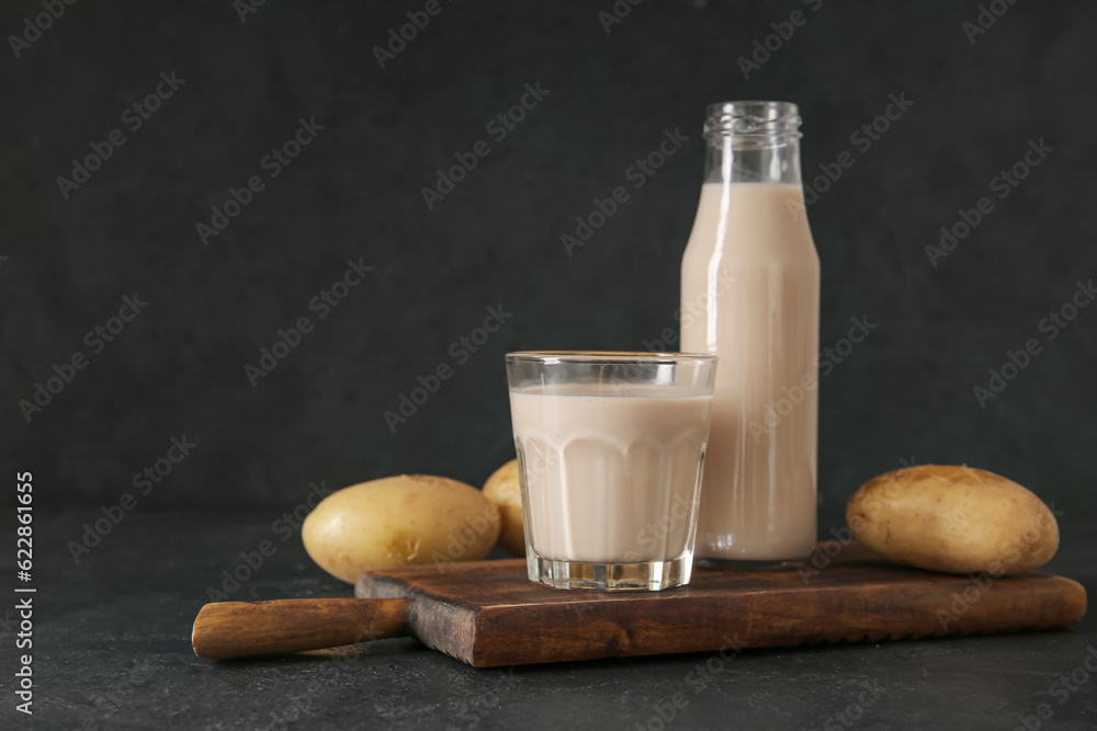 Bottle and glass of tasty potato milk on black background