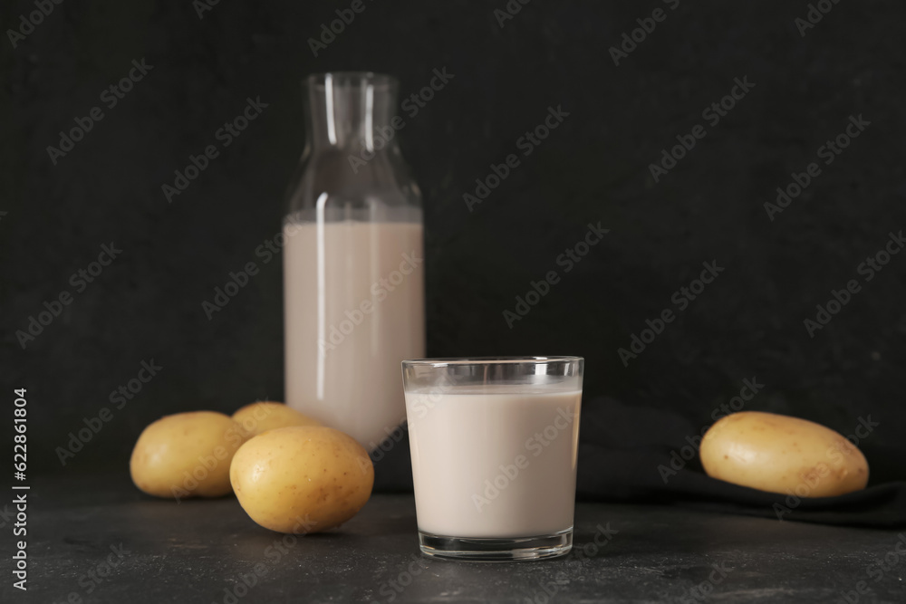 Glass of tasty potato milk on black background