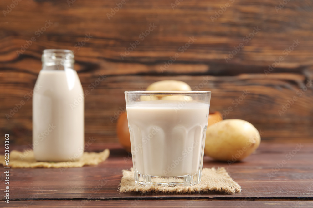 Glass of tasty potato milk on wooden background