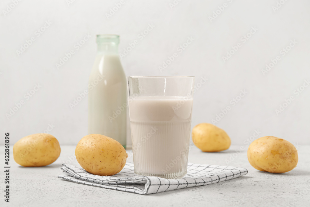 Glass of tasty potato milk on light background