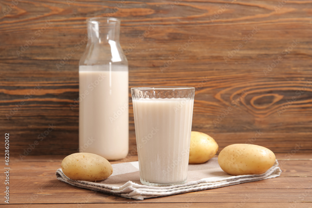 Glass of tasty potato milk on wooden background