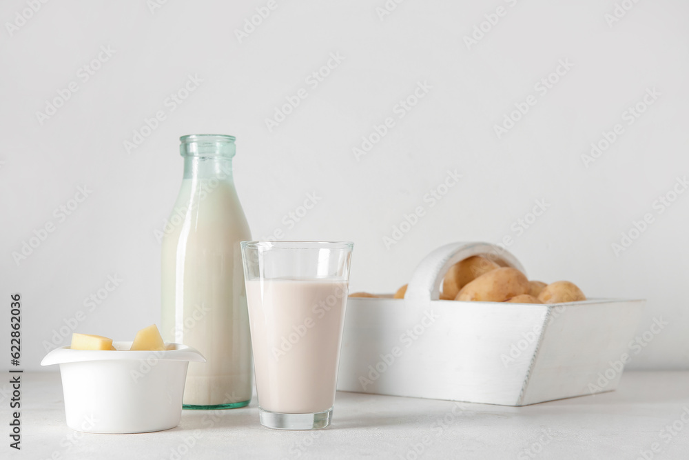 Bottle and glass of tasty potato milk on light background