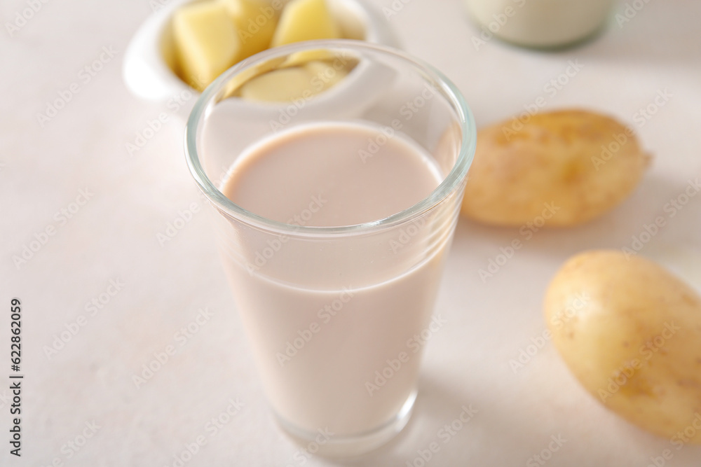 Glass of tasty potato milk on light background