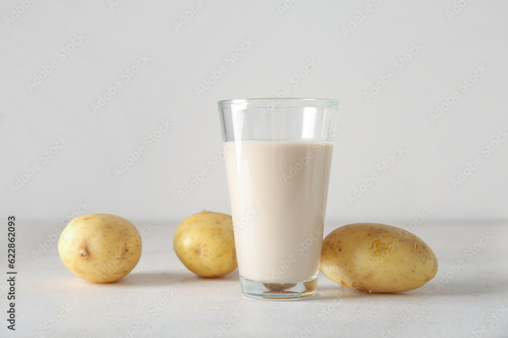 Glass of tasty potato milk on light background