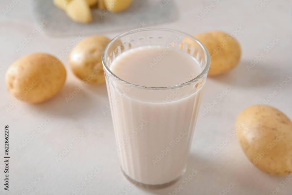 Glass of tasty potato milk on light background