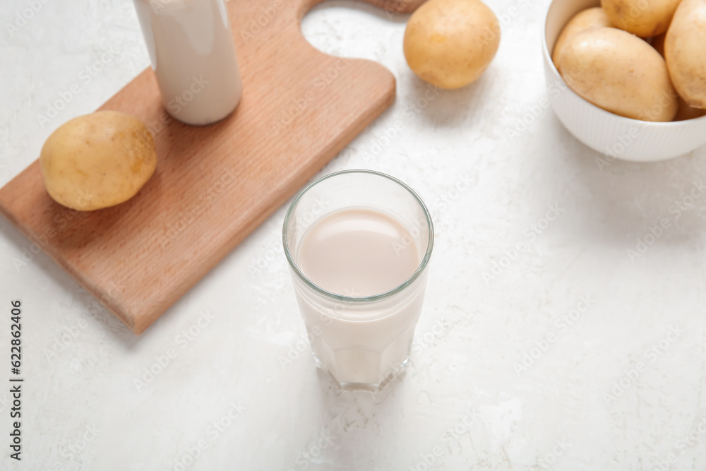 Glass of tasty potato milk on light background