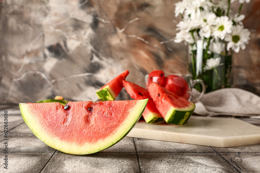 Board with pieces of fresh watermelon on grey tile table