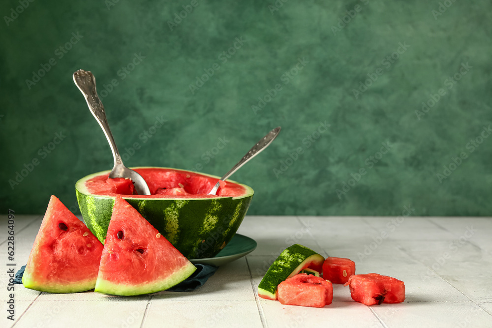 Plate with half of fresh watermelon and pieces on white tile table