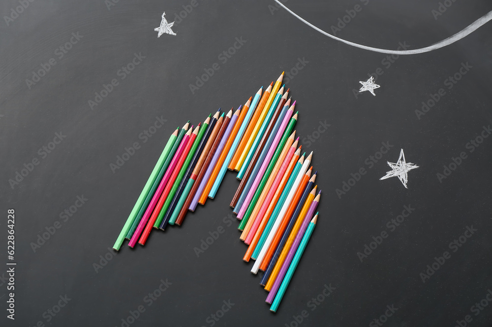 Pencils and drawn stars on black background