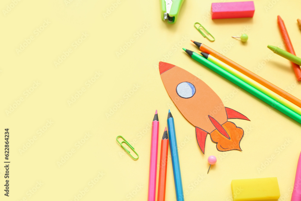 Paper rocket with school stationery on yellow background