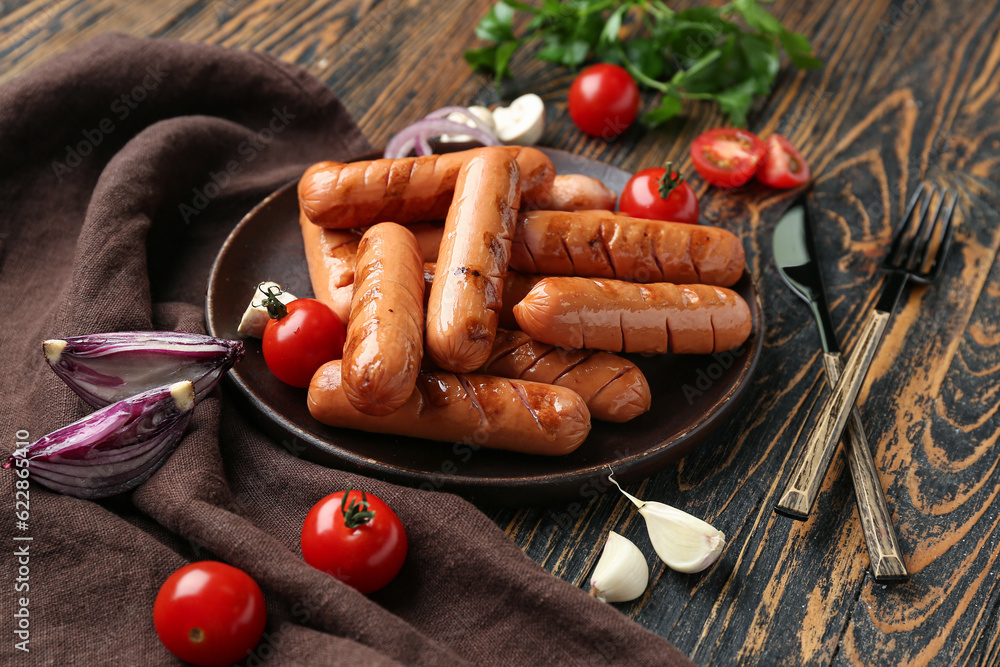 Plate with tasty grilled sausages and vegetables on wooden table, closeup