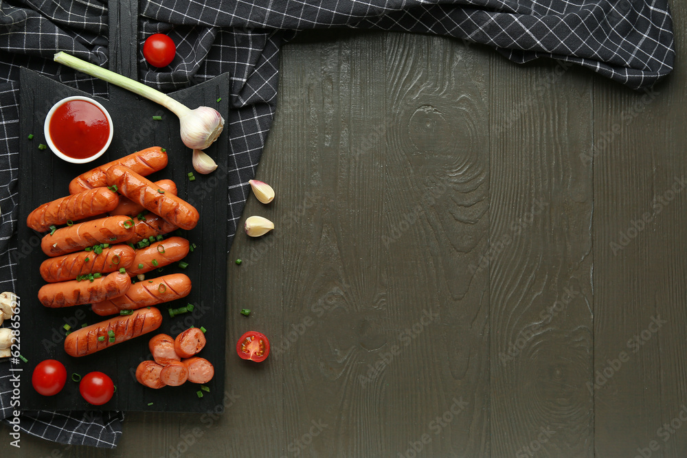 Board with delicious grilled sausages, garlic and ketchup on black wooden table